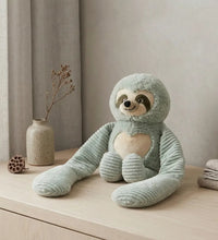 Weighted small sloth stuffed animal hugger in a cozy room setting